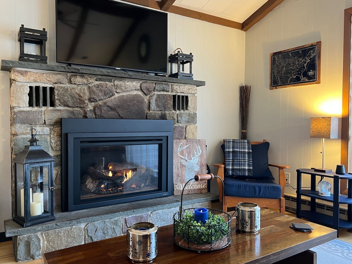 The lit stone gas fireplace in the living room at The Plaid Cabin